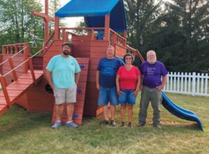 (From Left) Mongo Lions Ben Stager, Doug Newhouse, Susan Newhouse, and John Bremer in front of the refurbished Ark at the Mongo United Methodist Church. (Photo by Alice Bremer)