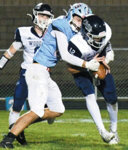 ALL WRAPPED UP—Lakeland defensive end Keegan Merrifield (89) tackles Woodlan quarterback Griffin Clear (12) for a loss in 3A football playoff action last Friday. The Laker defense held the Warriors scoreless while the offense put up 32 points in an easy LHS triumph. (Standard-News Photo by Jeff Miller)