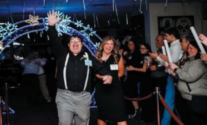Guest Tim Kauffman walks the red carpet with buddy Madison Bateman as guests cheer them on during Night to Shine. The two look forward to being paired together each year for the special event. Photo Contributed)
